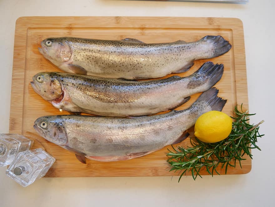rainbow trout on a cutting board with lemon and thyme
